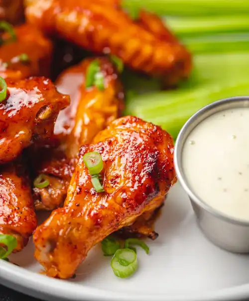 Spicy buffalo chicken wings served with celery sticks and creamy dipping sauce